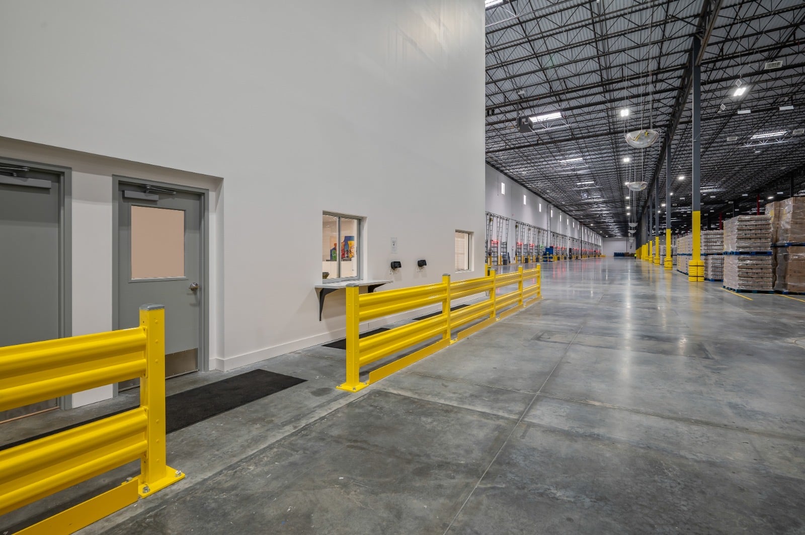 Distribution facility corridor with yellow guardrails and sealed concrete